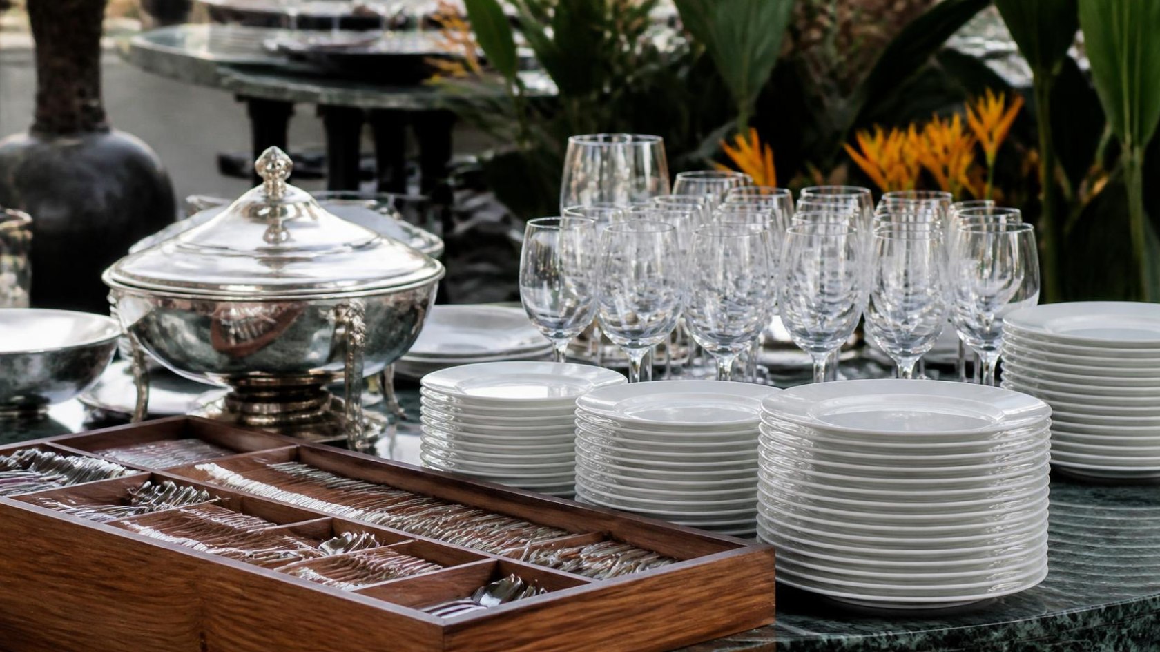 Itens de buffet organizados: pratos, taças, talheres e travessas